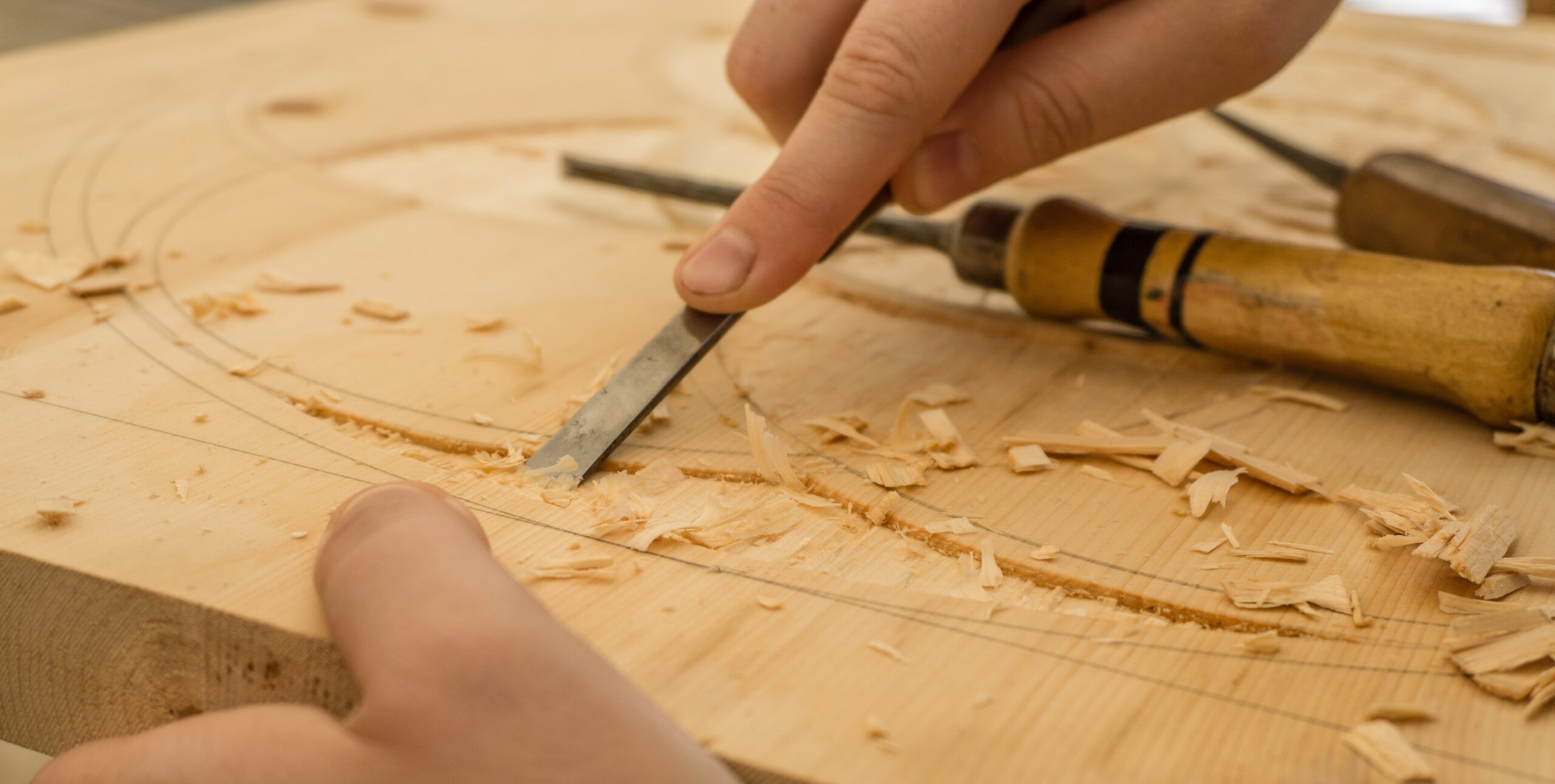 Hand on chisel, carving into wood